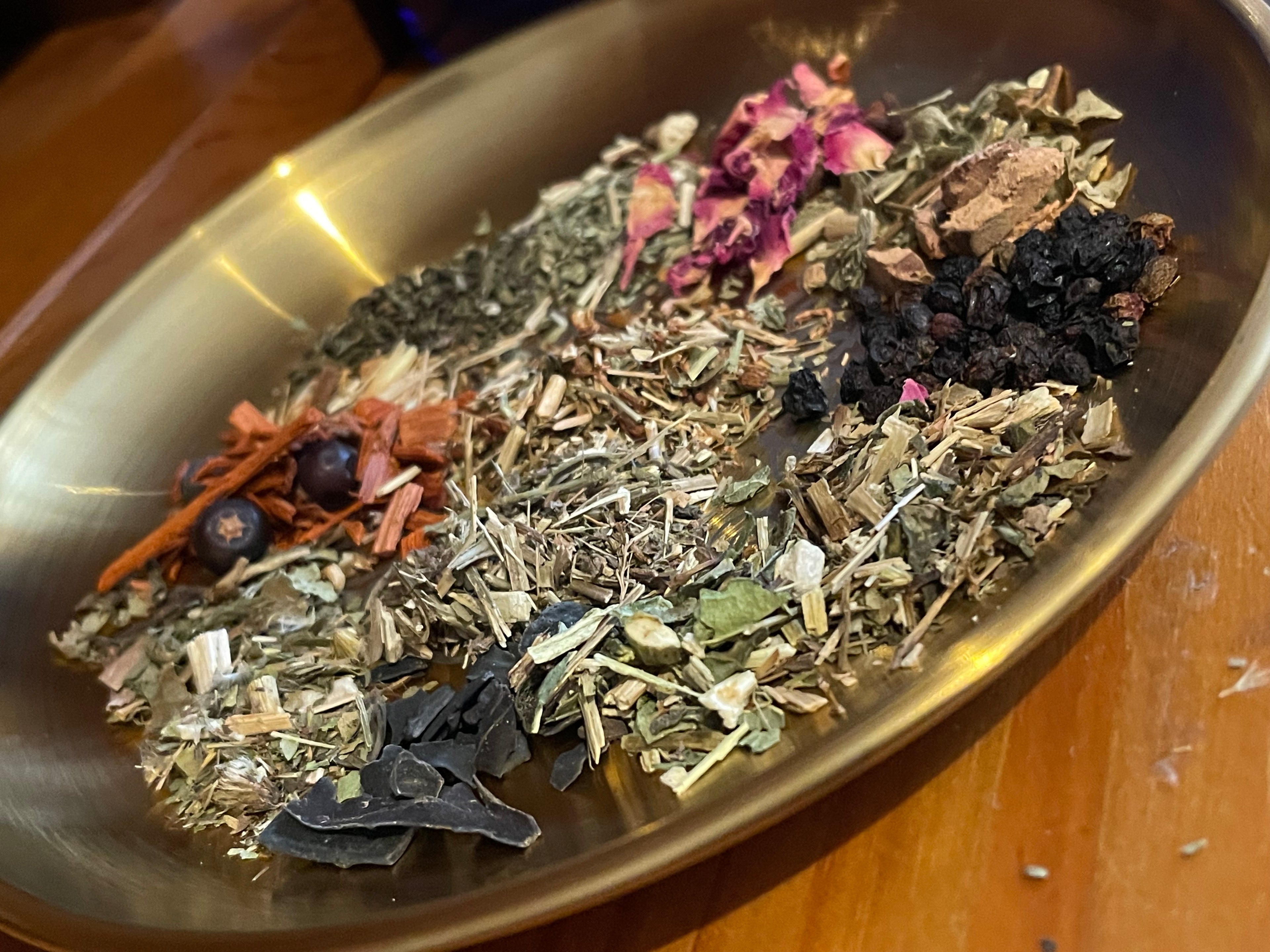 A selection of dried herbs from a UK apothecary for herbal teas and herbal remedies. They are on a copper plate.