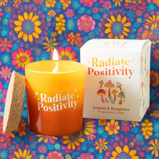 Radiate Positivity Lemon & Bergamot Candle in vibrant yellow and orange glass pot, promoting uplifting scents and positive vibes for any living space.